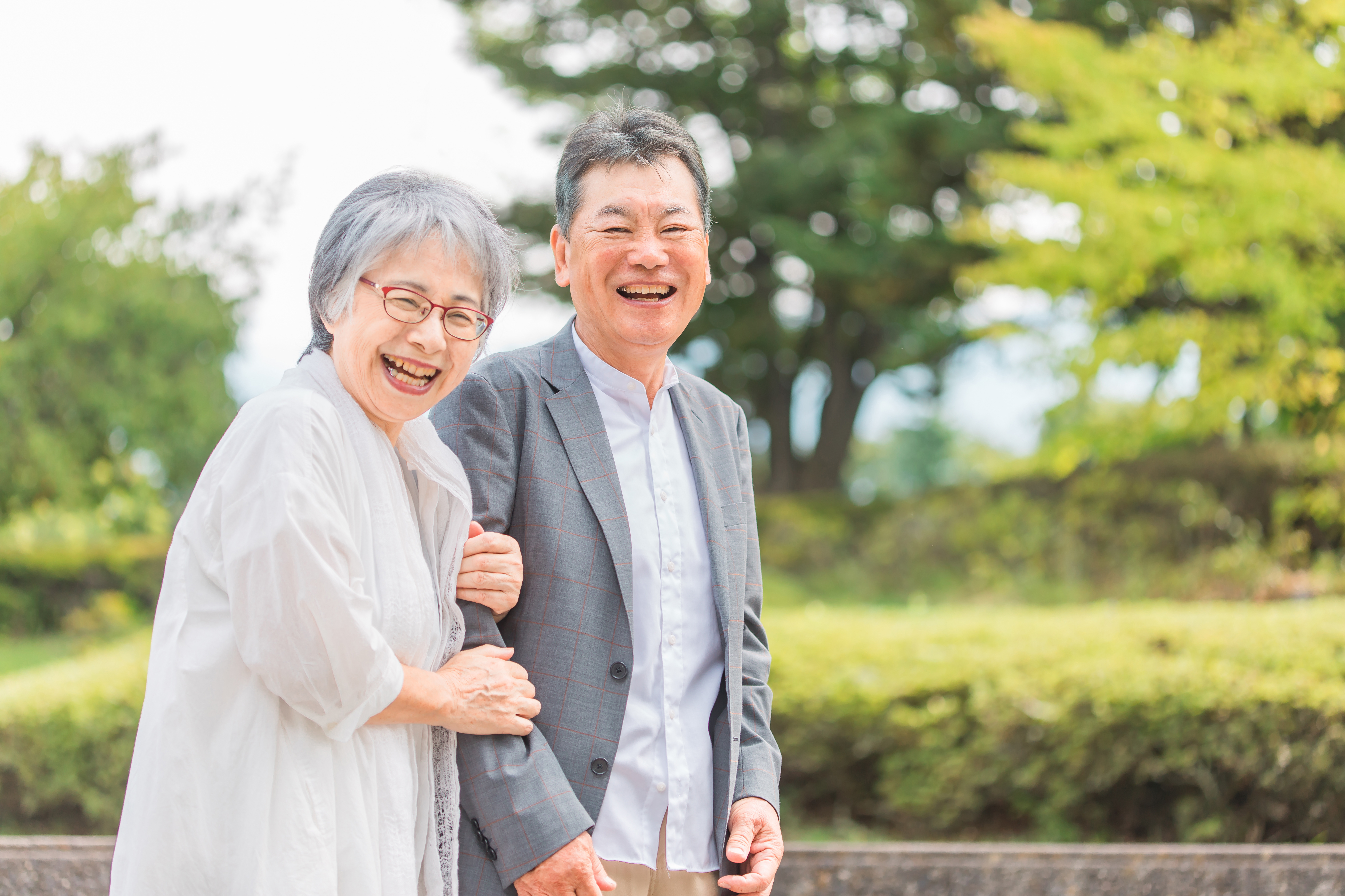 公園を歩く老夫婦（カメラを見ながら）