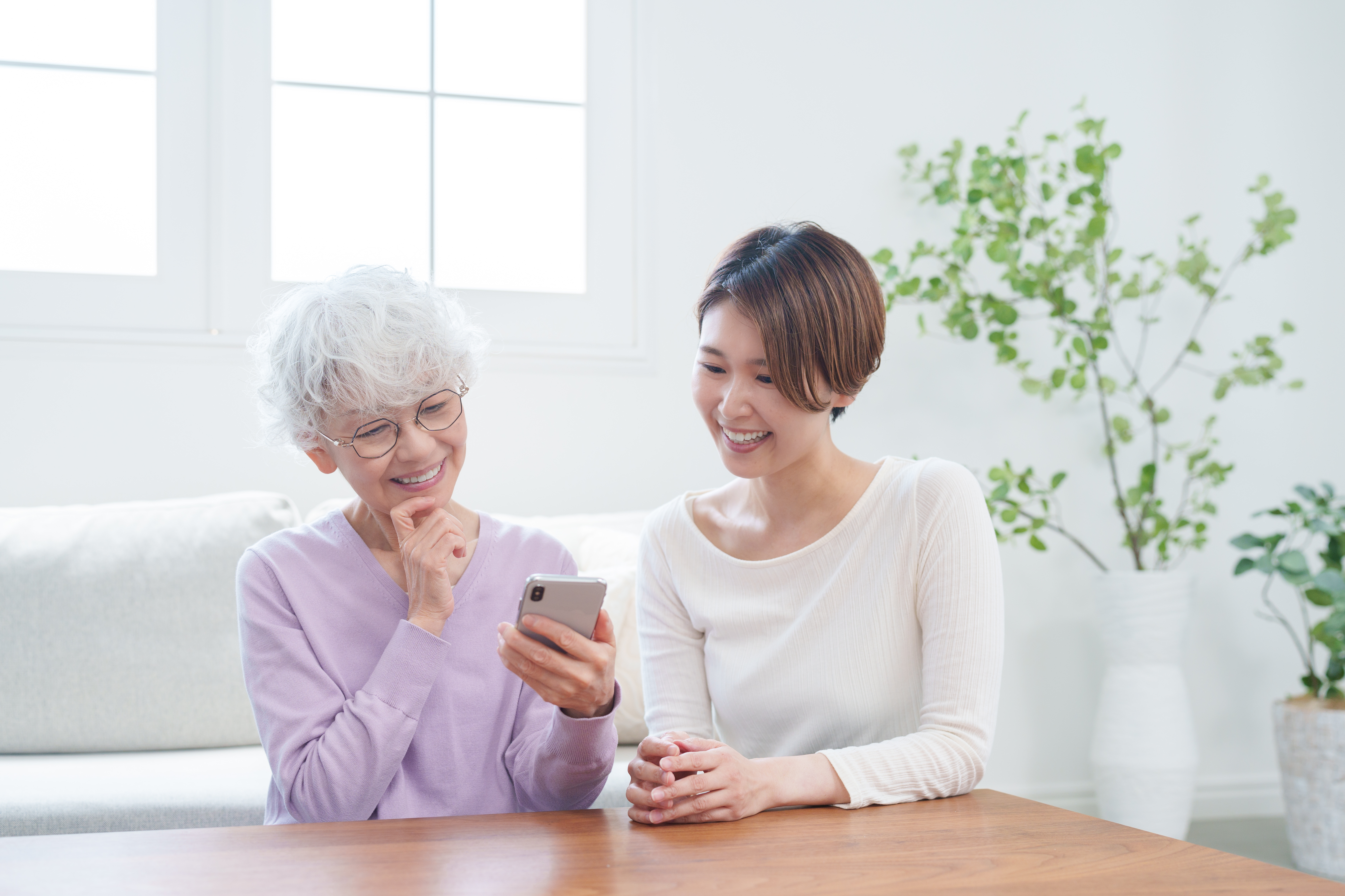 高齢者の母親にスマホを教える娘（家族・ファミリー）